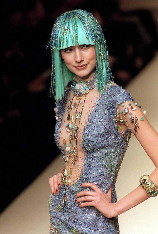 1998年1月20日，一名模特在巴黎路易斯·費勞1998年春夏高級時裝系列上展示一件繡有藍色和綠色珠子、亮片、金線和流蘇珠寶的低胸透明緊身長裙。 - 俄羅斯衛星通訊社