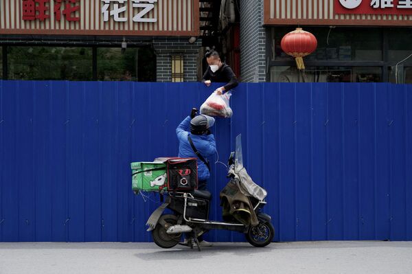 2022年5月11日，在北京新冠疫情封鎖下，一名送貨員將物品傳遞給圍欄住宅區內的一名男子。 - 俄羅斯衛星通訊社