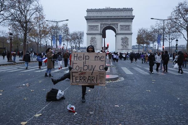 一名法國男子在巴黎凱旋門前手持“請幫我買一輛法拉利”標語牌。 - 俄羅斯衛星通訊社