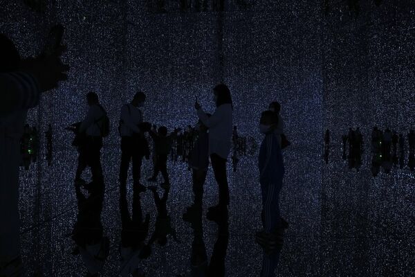 2022年12月26日(周一)，在北京新开放的“teamLab mass - less”博物馆，游客们在体验名为“无限水晶宇宙”的沉浸式数字艺术装置时看到剪影。由东京艺术团队teamLab设计的“teamLab Massless”在首都北京的一个购物中心内创建了一个数字艺术博物馆，展示各种互动艺术品。(美联社图片/Andy Wong) - 俄罗斯卫星通讯社