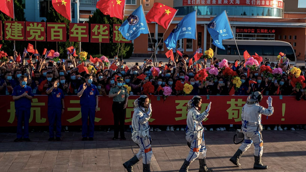 Astronauts Nie Haisheng (R), Liu Boming (C) and Tang Hongbo wave during a departure ceremony before boarding the Shenzhou-12 spacecraft on a Long March-2F carrier rocket at the Jiuquan Satellite Launch Centre in the Gobi desert, in northwest China on June 17, 2021. - 俄罗斯卫星通讯社