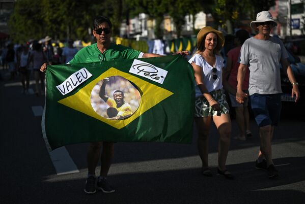 巴西桑托斯，球迷手持繪有球王貝利頭像的巴西國旗，前往維拉貝爾米羅體育場悼念球王。 - 俄羅斯衛星通訊社