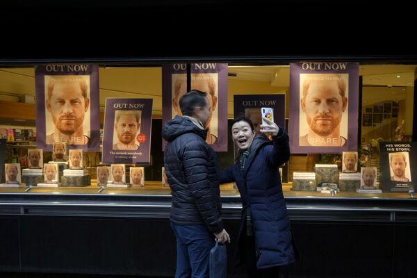 倫敦，一對夫婦在書店的櫥窗前拍照，裡面展示了哈里王子的自傳回憶錄《備胎》。 - 俄羅斯衛星通訊社