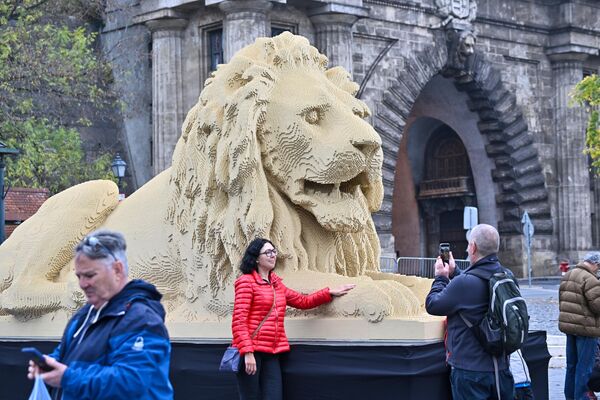 游客在巨大的乐高狮子雕像前摆姿势，它精细复制了匈牙利布达佩斯最古老的链桥上其中的一座狮子雕像。 - 俄罗斯卫星通讯社