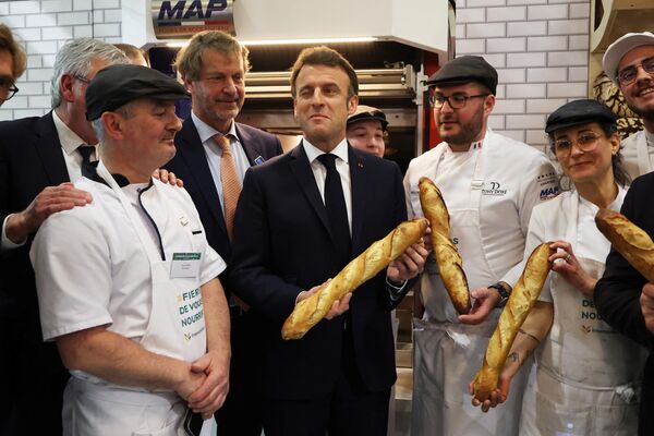 2023年2月25日，第59届法国国际农业博览会的第一天，法国总统马克龙（中）在面包师展台上与法棍合影。 - 俄罗斯卫星通讯社