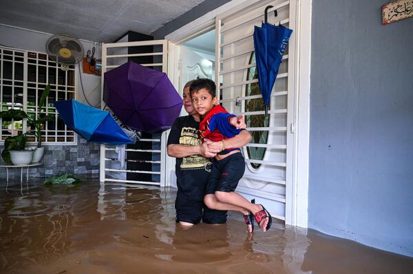一名女子抱著孩子離開被洪水淹沒的房子 - 俄羅斯衛星通訊社