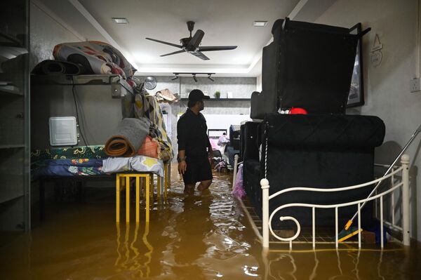 一名男子在撤離前評估自家房屋因洪水造成的損失 - 俄羅斯衛星通訊社