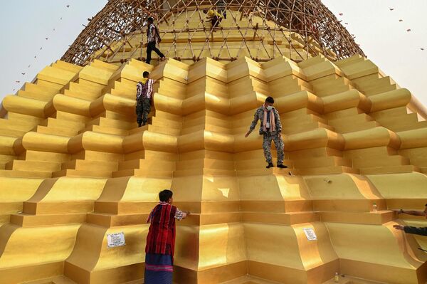 2023年3月5日，缅甸克伦邦，人们爬上佛塔参加佛教仪式，塔顶放置着一把吉祥金伞。(照片：AFP) - 俄罗斯卫星通讯社