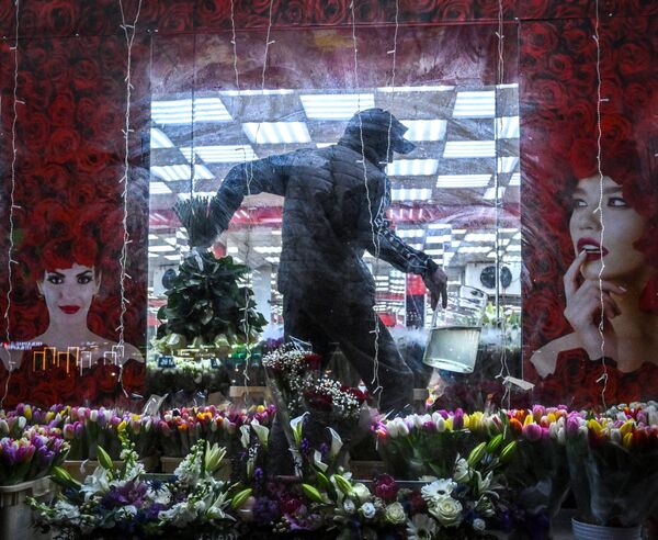 2023年3月6日，国际妇女节的前两天，一名花匠在莫斯科的一家花店搬运一束鲜花。(照片： Yuri KADOBNOV / AFP) - 俄罗斯卫星通讯社