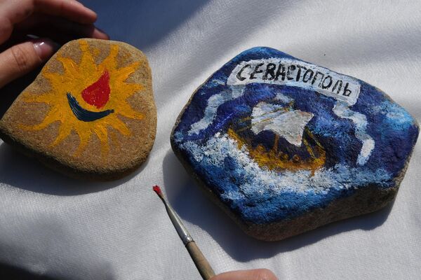 人們在符拉迪沃斯托克市中心舉行活動慶祝克里米亞入俄9週年，圖為活動現場一個姑娘在石頭上作畫。 - 俄羅斯衛星通訊社