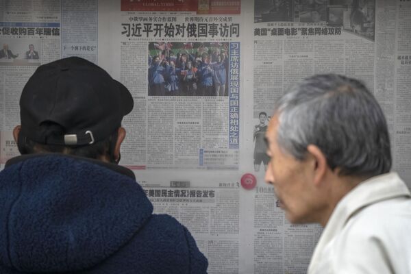 3月21日，人们在北京一处展示架上看着一份《环球时报》报纸，内容关于习近平访问俄罗斯。 - 俄罗斯卫星通讯社
