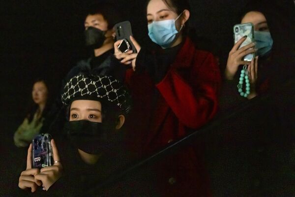 2023年3月26日星期日，在北京舉行的中國時裝周上，模特在展示中國時裝工作室D.Martina Queen的作品時，戴著口罩的觀眾在拍照。 - 俄羅斯衛星通訊社