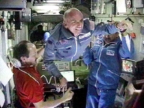 2001年4月30日，從電視上拍攝的這張圖片中，空間站指揮官尤里·烏薩奇夫（左）歡迎美國百萬富翁丹尼斯·蒂托（中）和俄羅斯宇航員塔爾加特·穆薩巴耶夫（右）來到國際空間站。 - 俄羅斯衛星通訊社