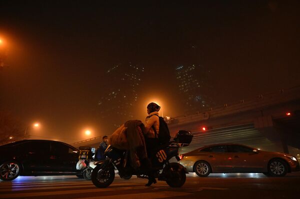 2023年4月10日，在北京的沙塵暴中，一名婦女騎著摩托車經過中央商務區。(照片：Jade Gao / AFP) - 俄羅斯衛星通訊社