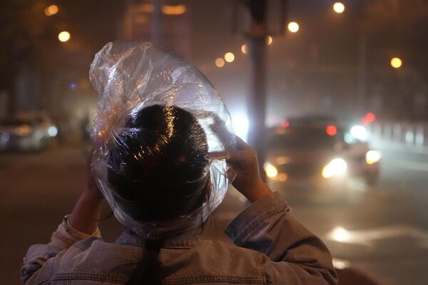 2023年4月10日，沙塵暴席捲北京，一位居民用塑料袋遮擋頭部。(照片：AP/Ng Han Guan) - 俄羅斯衛星通訊社