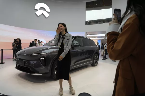 2023年4月18日，中国汽车制作商蔚来参展的最新电动汽车es6旁的一位女子。全天下以及中国的汽车制作商妄想在上海车展上推出十多少款新型电动suv、轿车以及高功能轿跑，这是他们四年来在已经成为研发电动汽车、自动驾驶汽车以及其余技术的市场上的初次周全销售行动。(Ng Han Guan/美联社) - 俄罗斯卫星通讯社