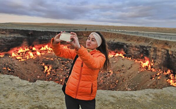 2019年3月21日，一名女孩站在土库曼斯坦卡拉库姆沙漠燃烧的火山口“地狱之门”前自拍。 - 俄罗斯卫星通讯社