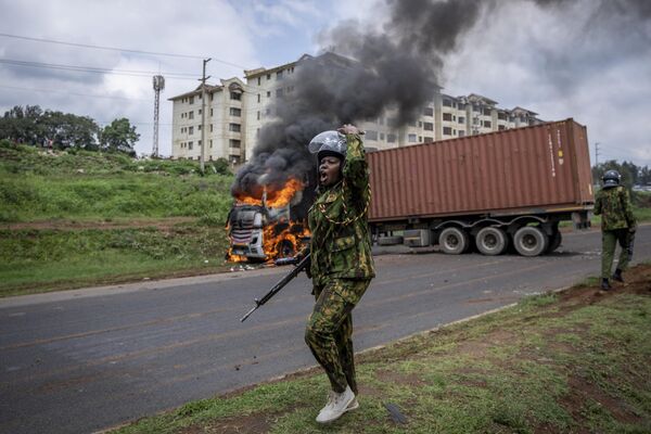 2023年5月2日星期二，在肯尼亚首都内罗毕的基贝拉贫民窟，反对派抗议者因未能打开运输集装箱而点燃了一辆卡车，一名防暴警察呼吁增援。反对派领导人奥廷加呼吁举行新一轮示威活动，要求采取行动解决生活成本问题，并对选举委员会进行改革。该委员会去年监督了总统鲁托赢得的选举。(美联社/Ben Curtis) - 俄罗斯卫星通讯社