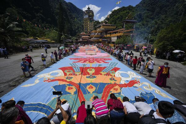 2023年5月4日星期四，马来西亚怡保卫塞节庆祝活动期间，信徒们在阳光下揭开一幅巨大的神圣“唐卡”画布，画布长60米(197英尺)，宽12米(39英尺)。卫塞节是佛教徒最神圣的日子之一，为所有信徒提供了一个机会，不仅庆祝佛陀的生日，还庆祝他的觉悟和涅槃的成就。(美联社/Vincent Thian) - 俄罗斯卫星通讯社