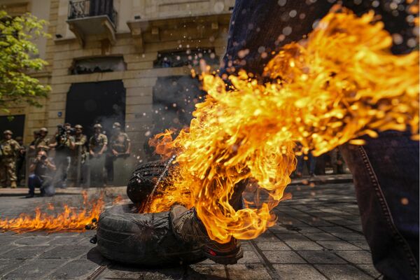 贝鲁特抗议活动期间，一名抗议者在银行协会大楼前踢了一个正在燃烧的轮胎。 - 俄罗斯卫星通讯社