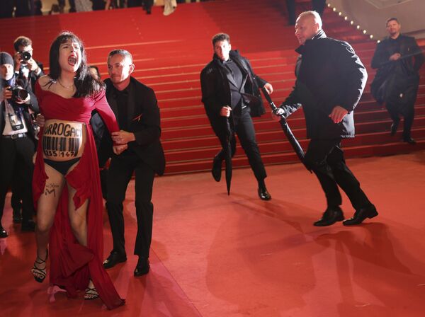 在戛纳第76届国际电影节影片《回家》首映式期间，保安将一名腹部写有“代孕”字样的抗议者从红地毯上拖离。 - 俄罗斯卫星通讯社