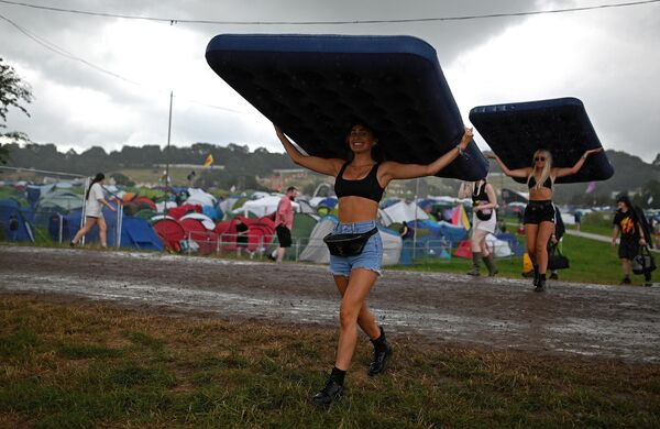 英格兰萨默塞特郡，格拉斯顿伯里音乐节的游客在雨中顶着充气床垫行走 - 俄罗斯卫星通讯社