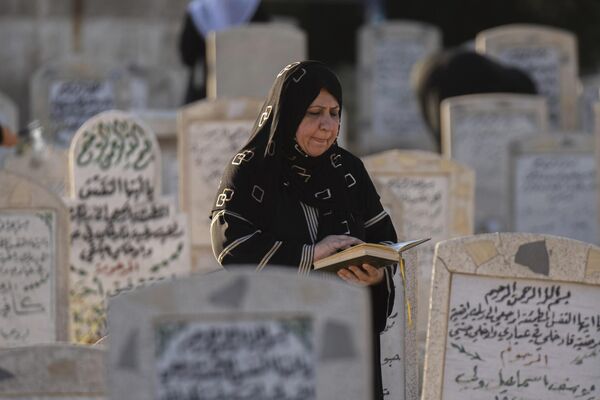 一名伊拉克婦女在親戚墓前閱讀《古蘭經》。 - 俄羅斯衛星通訊社