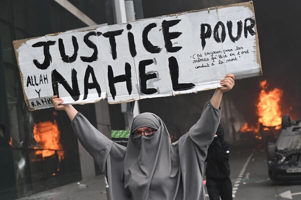 巴黎郊區楠泰爾，警察槍殺少年抗議遊行結束時，一名抗議者在燃燒的汽車前舉著一張寫有“為他媽的正義”的標語。 - 俄羅斯衛星通訊社