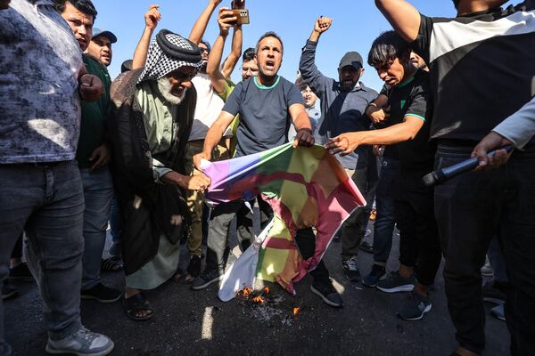 什叶派穆斯林领袖穆克塔达·萨德尔的支持者在瑞典驻巴格达大使馆附近焚烧彩虹旗帜，他们因一名居住在瑞典的伊拉克人焚烧了《古兰经》而闯入大楼。 - 俄罗斯卫星通讯社