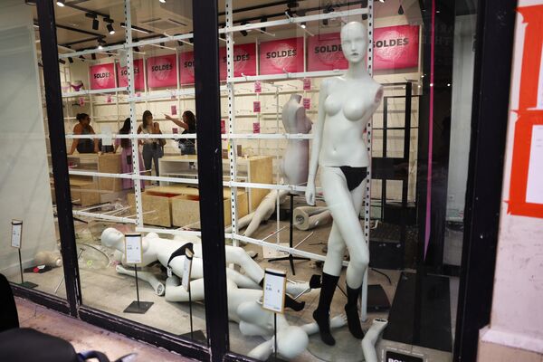 7月1日，法国马赛市中心一家受损且被抢劫的服装店内，店员们在打手势，背景标语牌上写着“促销”。 - 俄罗斯卫星通讯社