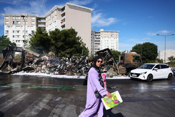 7月1日，法国马赛北部一家阿尔迪商店附近，一名行人走过一辆被烧毁的卡车。 - 俄罗斯卫星通讯社