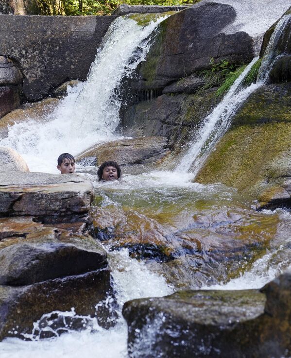 2023年7月6日星期四，在新罕布什尔州巴特利特，气温徘徊在90多华氏度，男孩们漂浮在戴安娜浴场的瀑布和水池中降温冲凉。戴安娜浴场是白山国家森林内的一个自然景点。 - 俄罗斯卫星通讯社