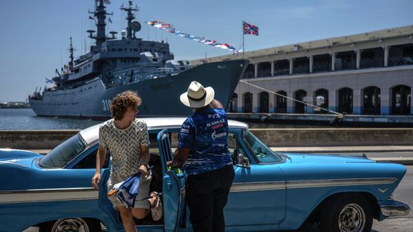 古巴游客从一辆经典的美国汽车里下车。远景为俄罗斯海军“佩雷科普”号训练舰 - 俄罗斯卫星通讯社