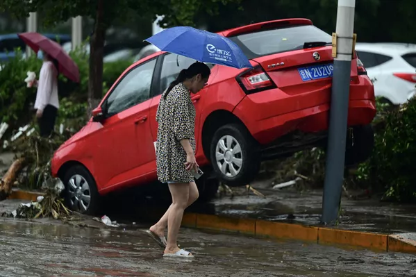 2023年7月31日，红色北京门头沟区，一位女性从暴雨后街道上一辆受损的汽车旁走过。(Pedro PARDO/法新社） - 俄罗斯卫星通讯社