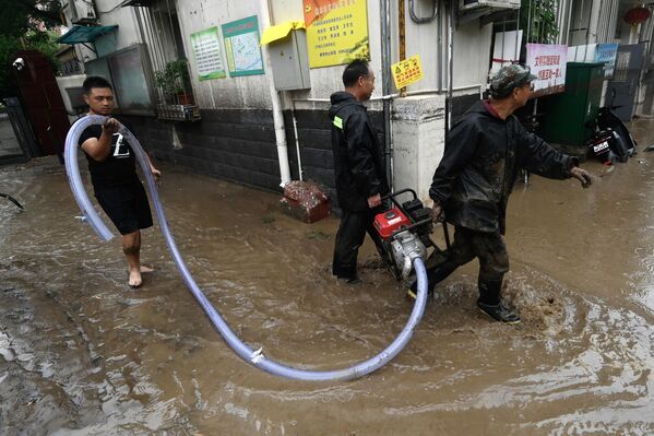 2023年7月31日，北京门头沟区，暴雨过后，几名男子抬着抽水机沿街排水。(Pedro PARDO/法新社） - 俄罗斯卫星通讯社
