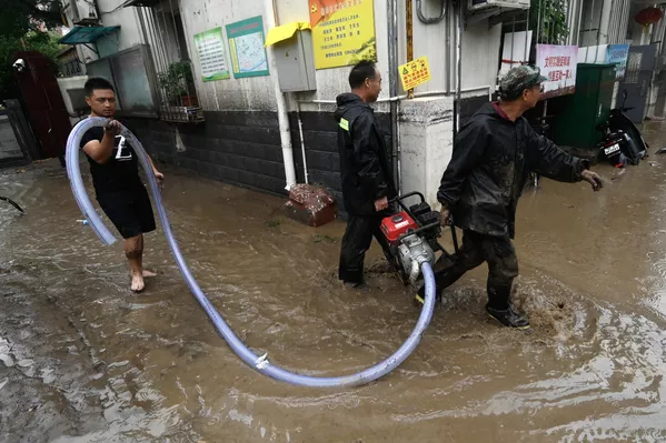 2023年7月31日，北京门头沟区，暴雨当时，多少名女子抬着抽水机沿街排水。(Pedro PARDO/法新社） - 俄罗斯卫星通讯社