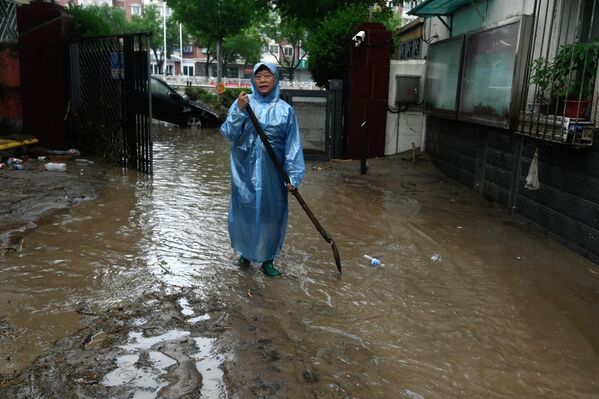 2023年7月31日，北京門頭溝區，暴雨過後，一名男子走在積水的街道上。(Pedro PARDO/法新社） - 俄羅斯衛星通訊社