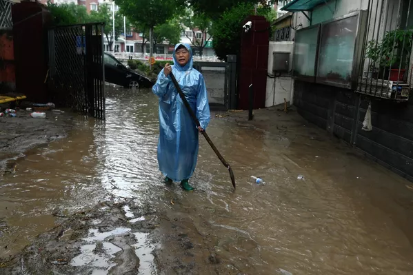 2023年7月31日，北京门头沟区，暴雨当时，一位女子走在积水的街道上。(Pedro PARDO/法新社） - 俄罗斯卫星通讯社