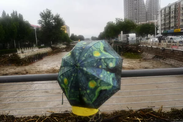 2023年7月31日，北京门头沟区，暴雨当时，一位当地居夷易近站在泛滥的永定河滨。(Pedro PARDO/法新社） - 俄罗斯卫星通讯社