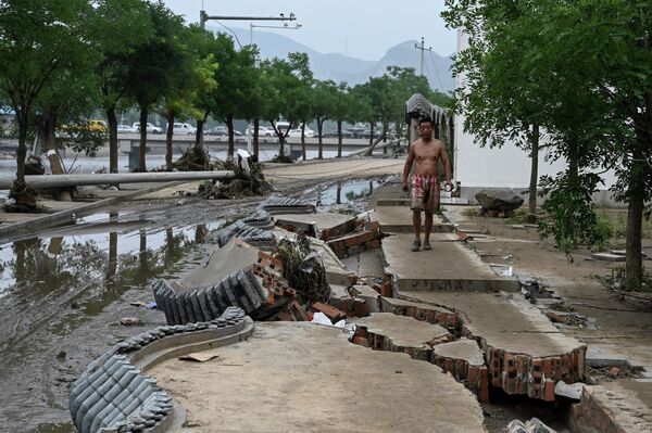 8月3日，北京强降雨过后，一个村庄遭遇洪水，一名当地居民在断墙上行走。 - 俄罗斯卫星通讯社