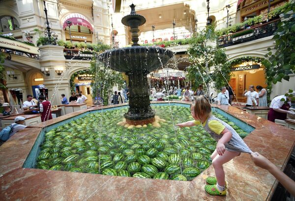 俄罗斯莫斯科，孩子们在古姆百货商场装满西瓜和甜瓜的主喷泉池边玩耍 - 俄罗斯卫星通讯社