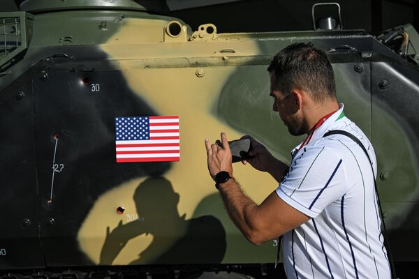 俄罗斯“军队-2023”国际军事技术论坛上，一名男子正在拍摄被俘获的装甲车上的弹孔。 - 俄罗斯卫星通讯社