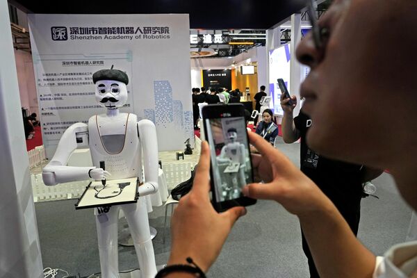 2023年8月16日星期三，在北京亦创国际会展中心举行的一年一度的世界机器人大会上，参观者正在记录一个可以为他们画像的机器人。 - 俄罗斯卫星通讯社
