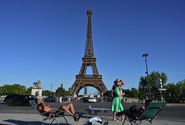 巴黎埃菲爾鐵塔前，路人從兩個在躺椅上享受日光浴的人身旁走過。 - 俄羅斯衛星通訊社