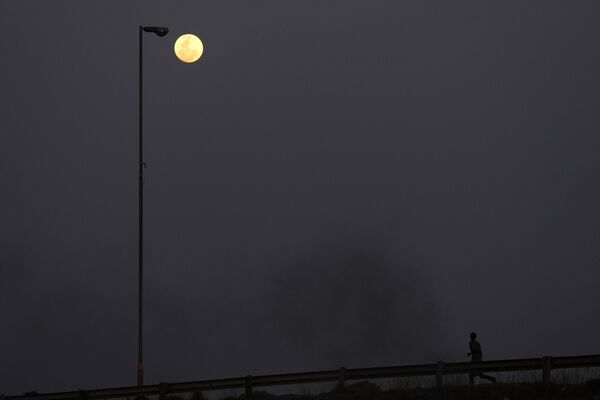 8月30日，南非約翰內斯堡以東的沃斯洛魯斯，一名男子在街上跑步，天空中出現超級月亮。 - 俄羅斯衛星通訊社