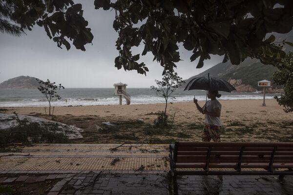 香港，海边村庄，在台风“苏拉”吹袭后，一名妇女正在拍摄被树枝覆盖的海滩 - 俄罗斯卫星通讯社