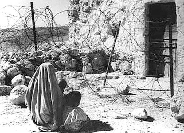 1948年拍攝的照片顯示一名巴勒斯坦難民和她的孩子在戰後被“綠線”與自家房屋分開。 - 俄羅斯衛星通訊社
