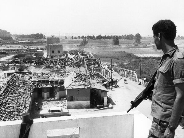 1967年6月22日，一名以色列士兵看著巴勒斯坦難民穿過飽受戰爭蹂躪的艾倫比橋，到達約旦東岸。 - 俄羅斯衛星通訊社