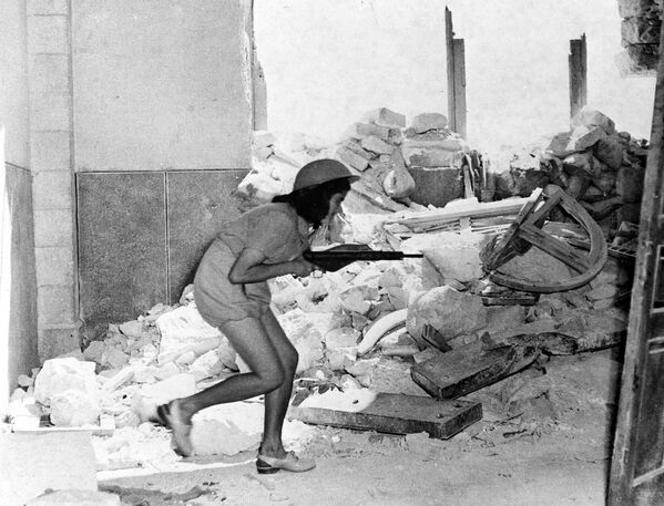 1948年7月20日，巴勒斯坦耶路撒冷老城，一名以色列士兵手持斯登槍，在蘇里曼路的破碎城牆中艱難前行。 - 俄羅斯衛星通訊社