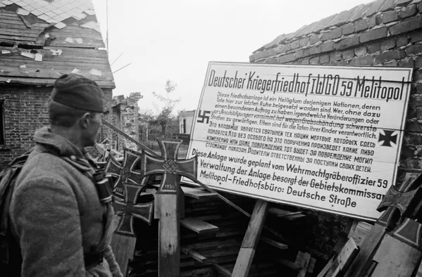 1943年10月，下第聂伯河战役，一苏联士兵正在读德国人制作的标牌：这个墓地是那些埋葬在这里的亡者们的圣地，任何人在没有特别指示的情况下进行任何改动甚至破坏都会因破坏坟墓而受到严厉惩罚，父母要为他们孩子的行为负责。 - 俄罗斯卫星通讯社